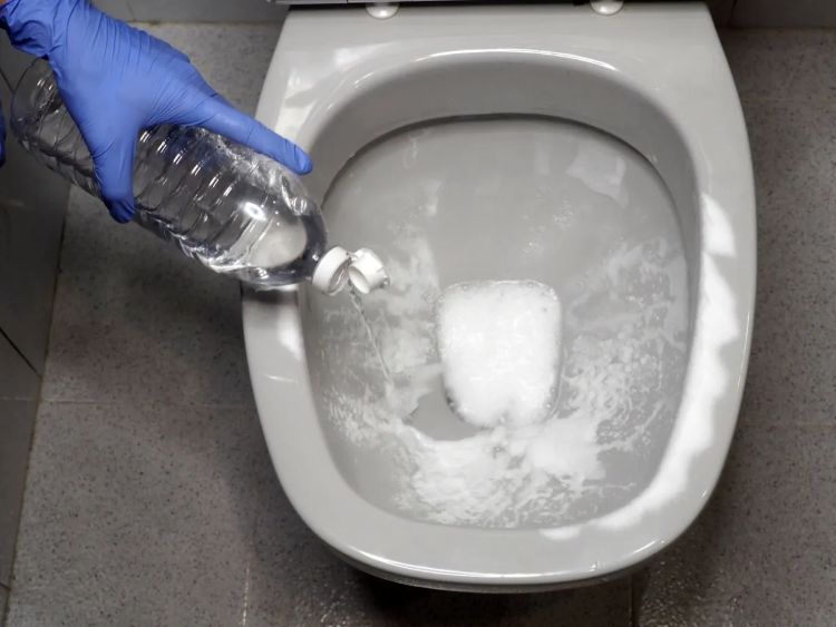 pouring vinegar and backing soda mixture into blocked toilet